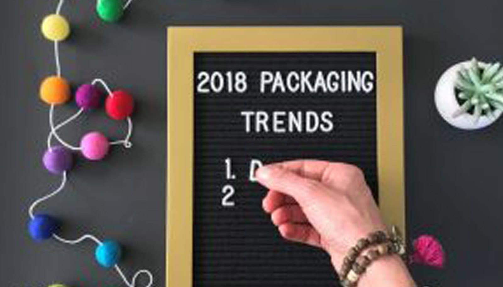 a woman's hand filling out a board that reads '2018 Packaging Trends'