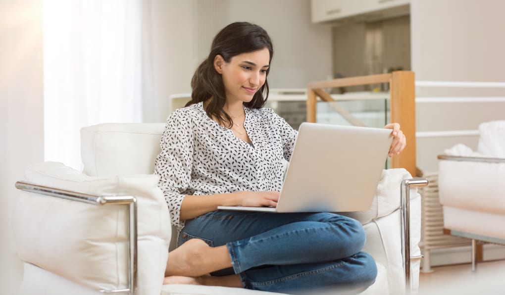 woman sitting on couch looking at laptop
