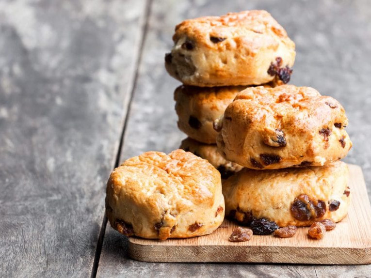 A photo of hearty scones, stacked on a wooden cutting board.