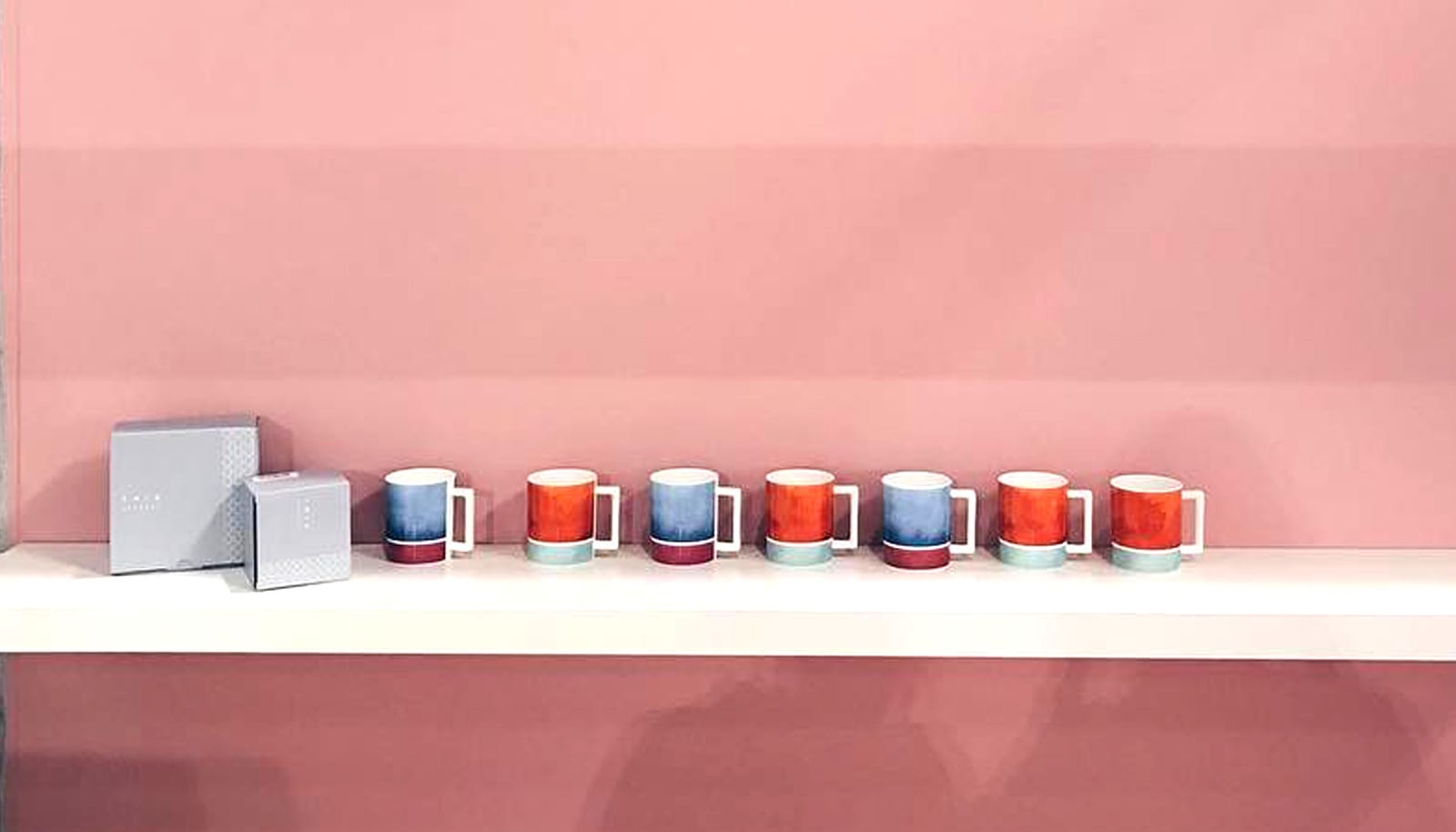 a row of mugs against a pink wall