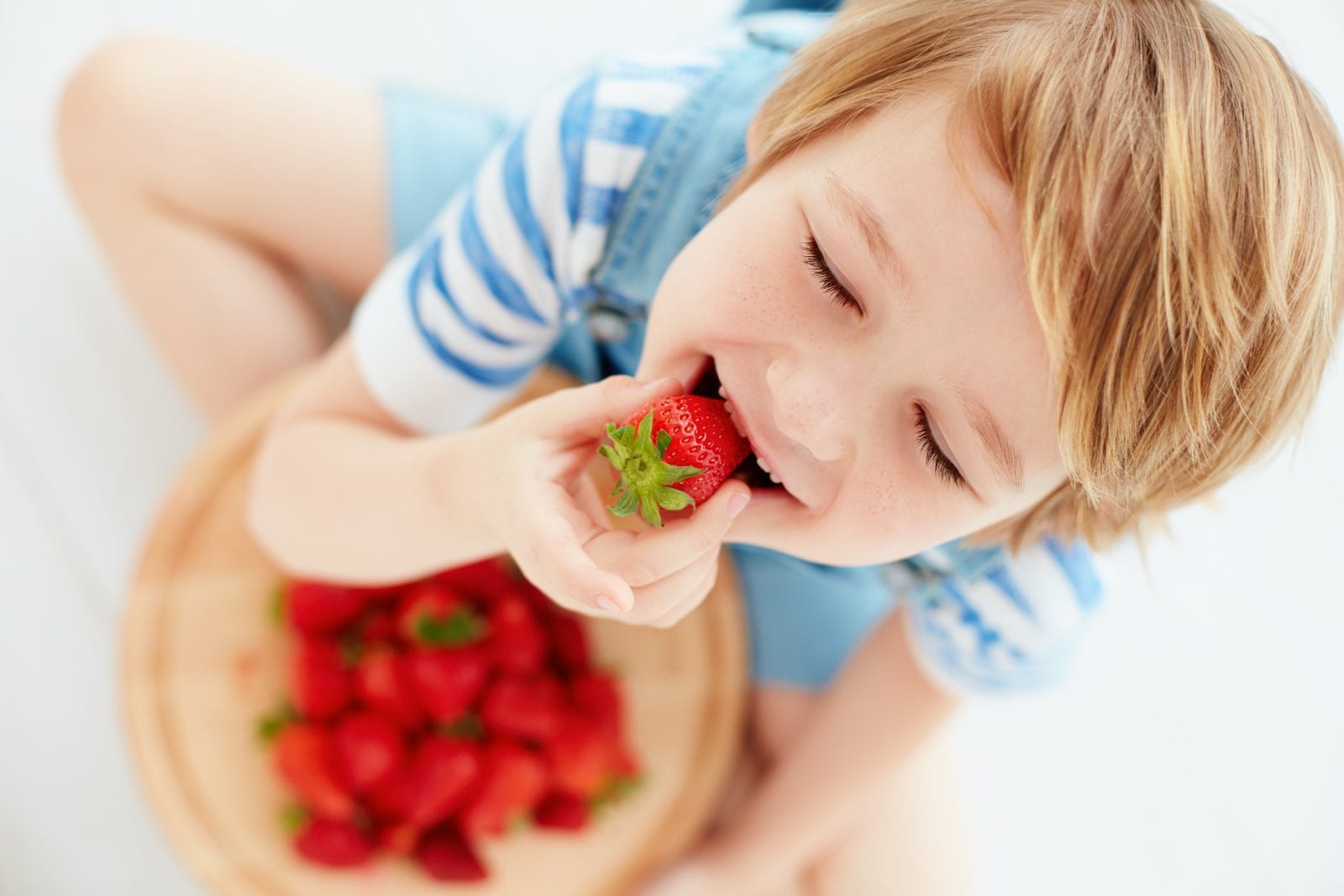 young boy eating strawberries